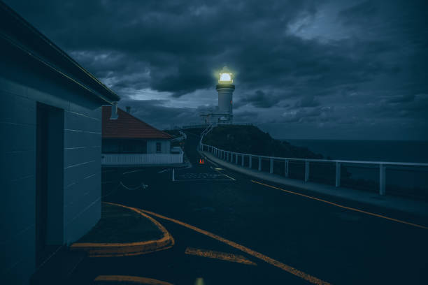 Witness the dramatic beauty of Cape Byron Lighthouse at sunset, perched on cliffs at Byron Bay, Australia, offering stunning views and a picturesque coastal landscape.
