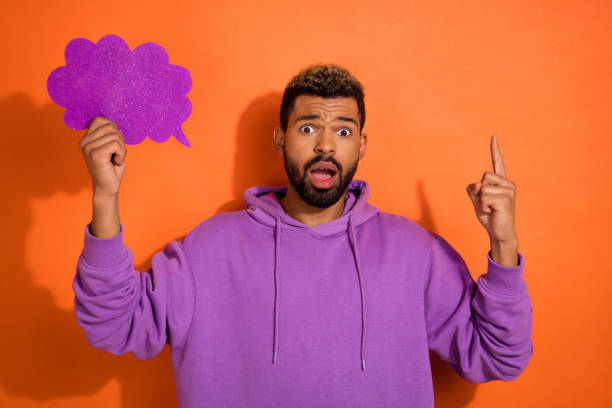 istock Portrait of impressed crazy handsome guy arm hold empty space cloud card point finger up empty space isolated on orange color background 2183632038