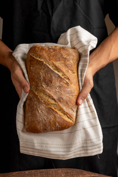 istock Person holding artisanal loaf against plain backdrop art 2183633471