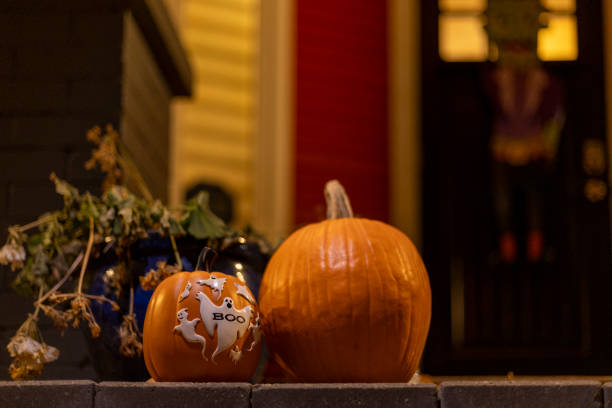 Two pumpkins are placed on a brick platform in the image, with one featuring white ghost designs and the word \