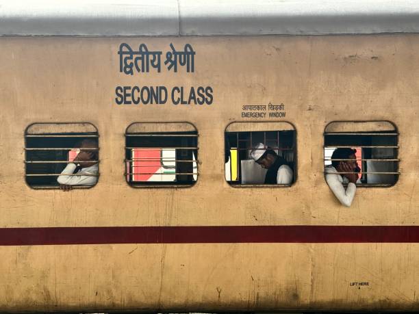 Railway Station, New Delhi, India - November 08, 2024 : Passengers in an ordinary railway compartment, sitting by the window, awaiting the start of their train on their journey.