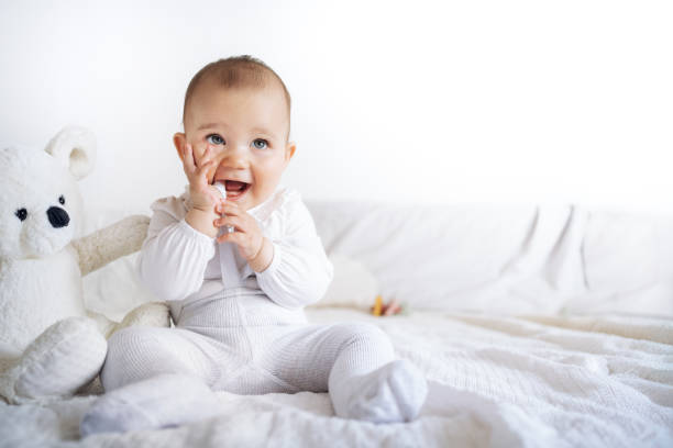istock Precious Baby Playing with Hands and Stuffed Teddy Bear on Bed 2183643912