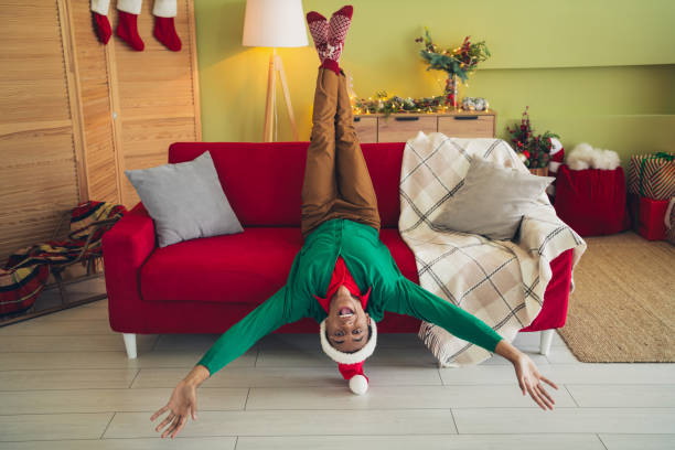 Photo of carefree good mood guy wear green sweater lying sofa celebrating noel xmas indoors room home house Photo of carefree good mood guy wear green sweater lying sofa celebrating noel xmas indoors room home house. black hat upside down stock pictures, royalty-free photos & images