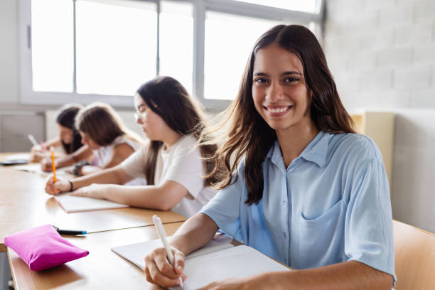 istock Happy student teen girl looking at camera while doing exercise at classroom 2183646021