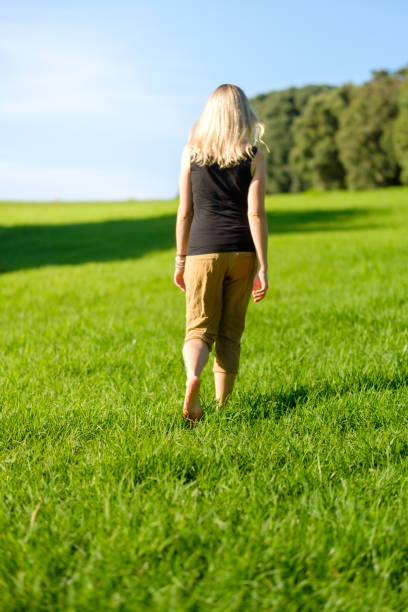 Woman walking on the grass barefoot. grounding / earthing