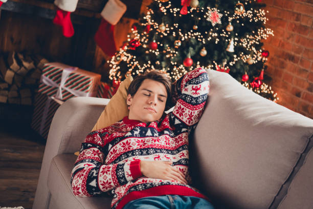 istock Photo of cheerful positive guy dressed ornament pullover sleeping couch enjoying x-mas eve indoors house apartment room 2183646356