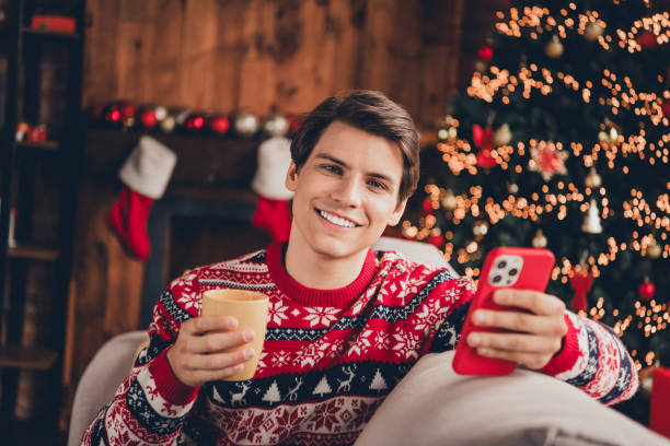 istock Photo of funky cool guy dressed ornament pullover enjoying x-mas day dringking cacao chatting modern gadget indoors house apartment room 2183646391