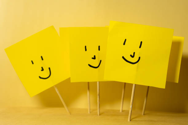 Group of yellow square papers with happy faces, concept of team joy