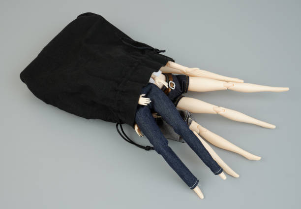 istock Many female dolls in black sack on gray background. 2183657217