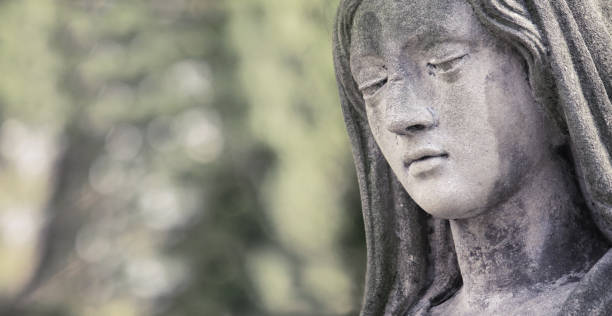 Old copper angel statue and a stone cross in a cemetery
