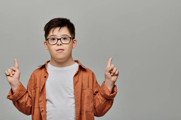istock A young boy with Down syndrome celebrates joyfully against a simple backdrop with raised fingers 2183663166