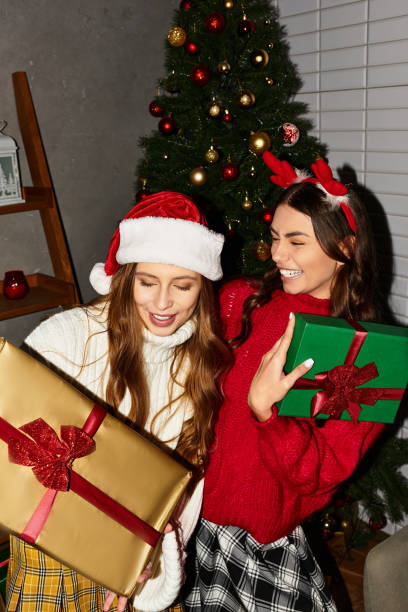 istock Two friends joyfully celebrating Christmas together by a beautifully decorated tree 2183663680