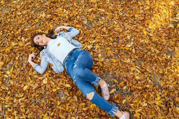 istock Young Woman Lying On Autumn Leaves 2183665445