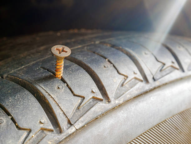 istock Close-up of a rusty screw driving into a car tire causing a puncture. 2183668854
