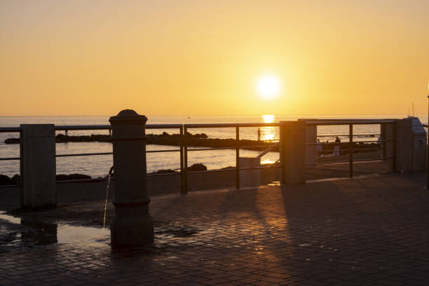 sunset in ostia lido near Rome with in foreground a fountain in backlight