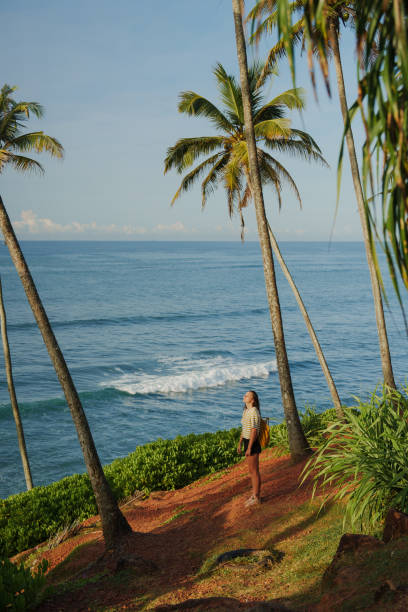 istock Woman looking at ocean standing among  palm trees grove 2183678543