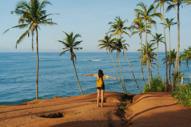 istock Woman looking at ocean standing among  palm trees grove 2183678552