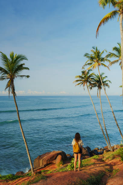 istock Woman looking at ocean standing among  palm trees grove 2183678595