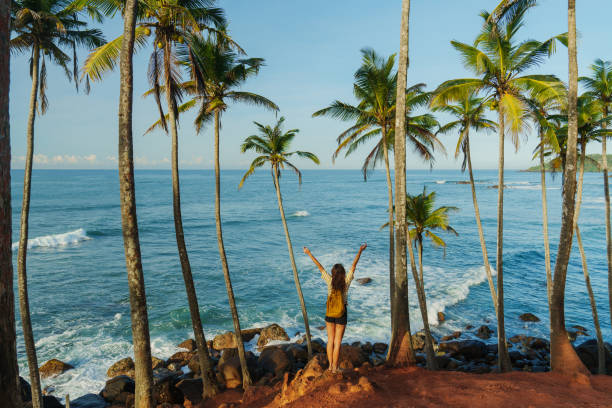 istock Woman looking at ocean standing among  palm trees grove 2183678655