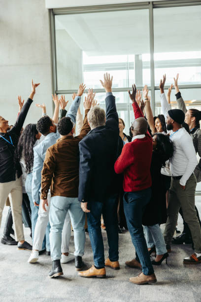 Diverse group celebrates success with teamwork and togetherness in a modern office setting