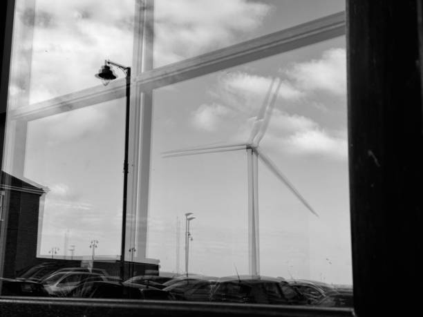 A wind turbine and a street lamp reflected in a window