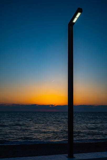 The sun is setting over the ocean, casting a warm glow on the water. The sky is a deep blue, with no clouds in sight. The beach is empty, with only the sound of the waves crashing against the shore