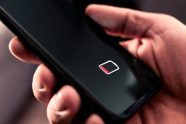 istock Phone battery with low charge. Cellphone with no power. Energy drain. Empty load and dead smartphone. Mobile recharge life icon symbol on screen. Man holding device in hand. 2183687699