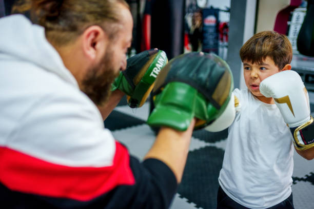 istock Focused young boy practicing boxing with his trainer in a gym. 2183692970
