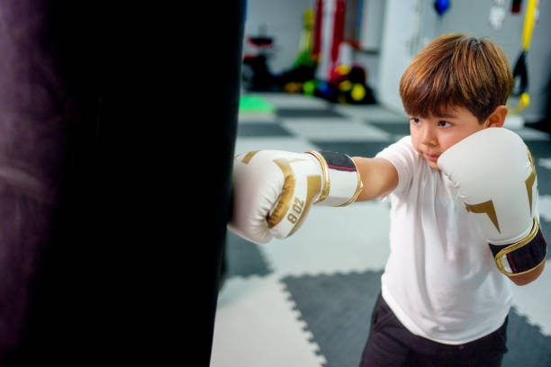 child athlete training on a punching bag in a gym.