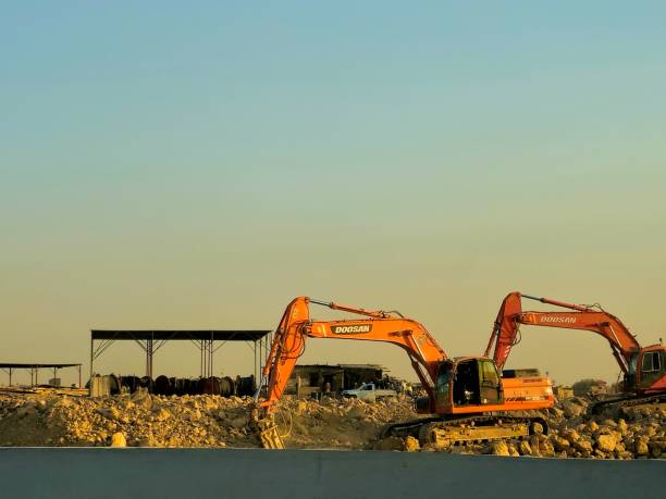 Cairo, Egypt, October 28 2024: demolition hydraulic crawler excavators and vehicles removing prats from a desert roadside for development and new high rise, Egyptian real estate road development