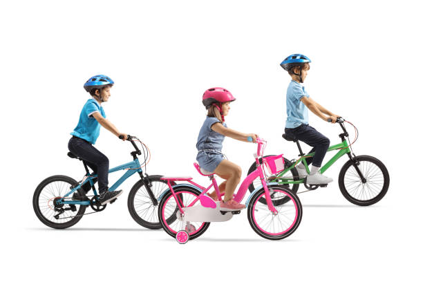 Excited kids in helmets sitting on their bikes with hands up in the air