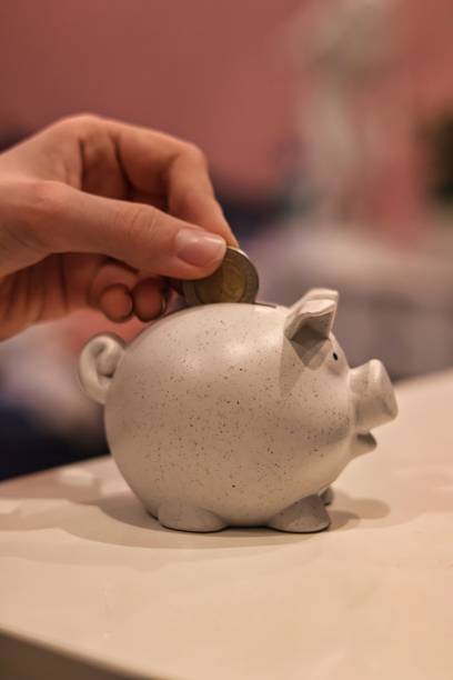 istock Saving; A hand throwing a coin into a piggy bank 2183709049