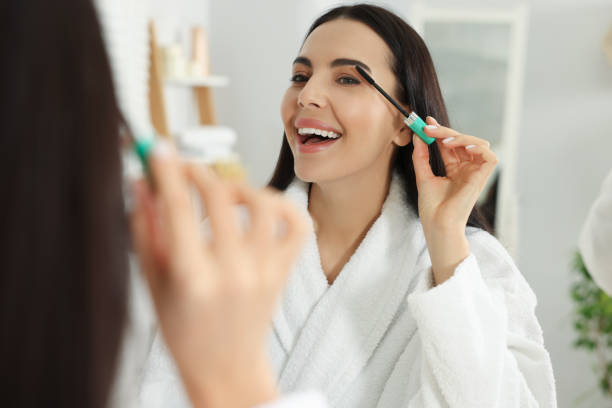 istock Beautiful young woman applying mascara in bathroom 2183714132