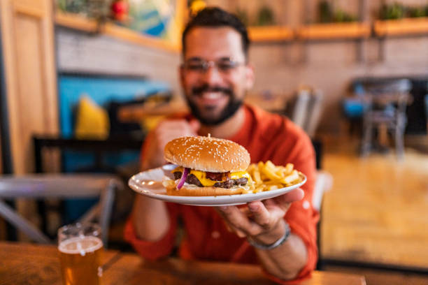 istock Young man holding a plate with a tasty burger 2183714856
