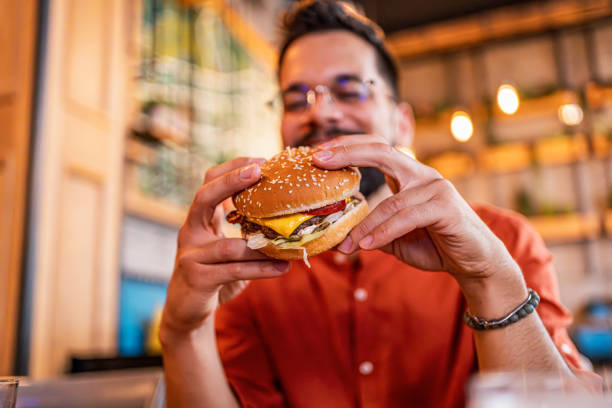 istock Young man eating a tasty burger 2183714871