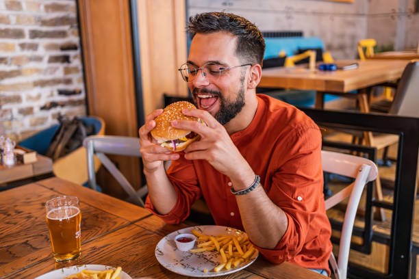istock Young man eating a delicious burger 2183714914