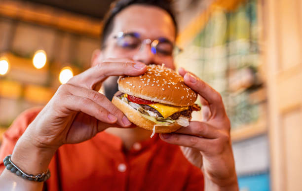 istock Young man eating a tasty burger 2183715217