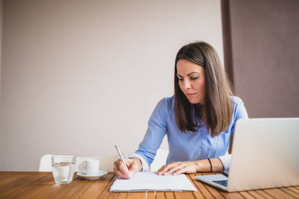 istock Working Woman Writing in Notebook at Desk at Home 2183715635