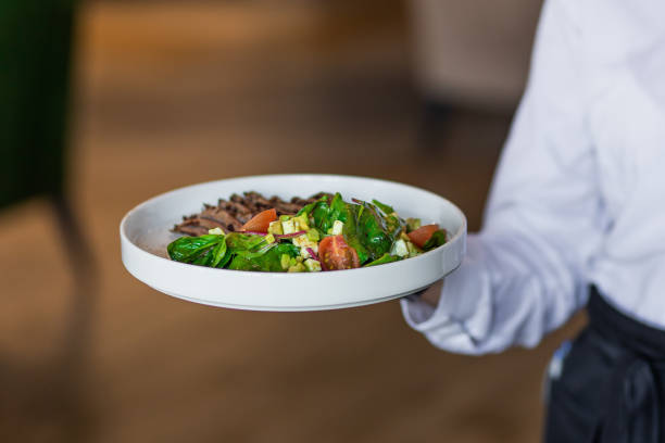 istock Appetizing salad served on a white plate by a waiter 2183715703