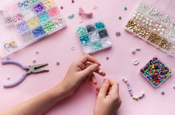 istock Crafting colorful jewelry with beads on a pastel workspace featuring tools and various materials 2183716184