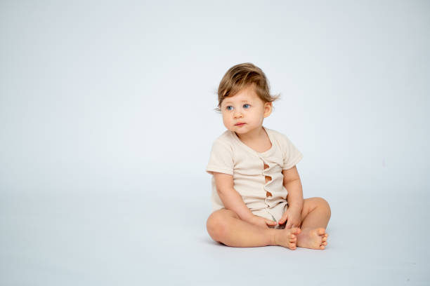 istock A baby boy is sitting on a white isolated background with a place for text in light clothes. A small happy child, space for text 2183717120