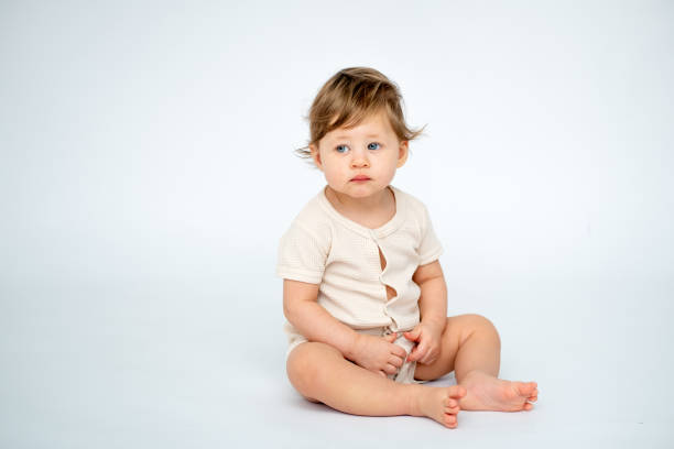 istock A baby boy is sitting on a white isolated background with a place for text in light clothes. A small happy child, space for text 2183717134