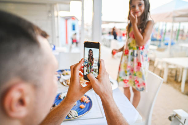 Father photographing daughter with mobile phone.