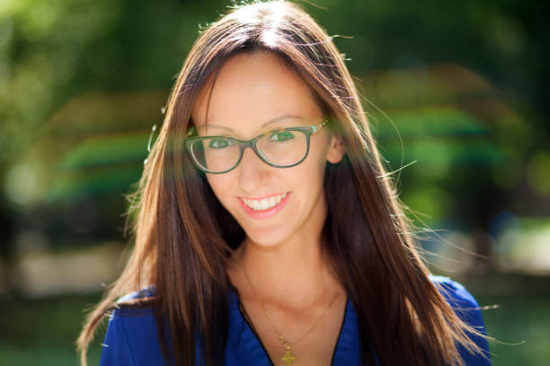 Portrait of a cheerful young woman wearing eyeglasses and smiling in a park