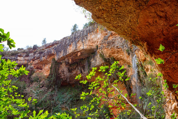 istock Serene Waterfall Cascading Down Rocky Cliffs Surrounded by Vibrant Green Foliage 2183727566