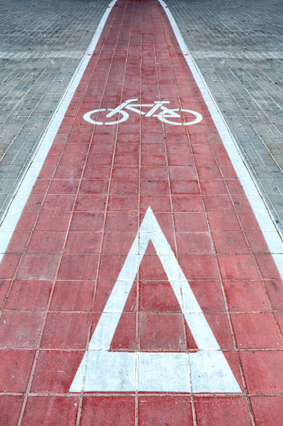 A vibrant red bicycle lane features clear markings of a bike symbol and a triangular warning sign, promoting safe cycling in the city.