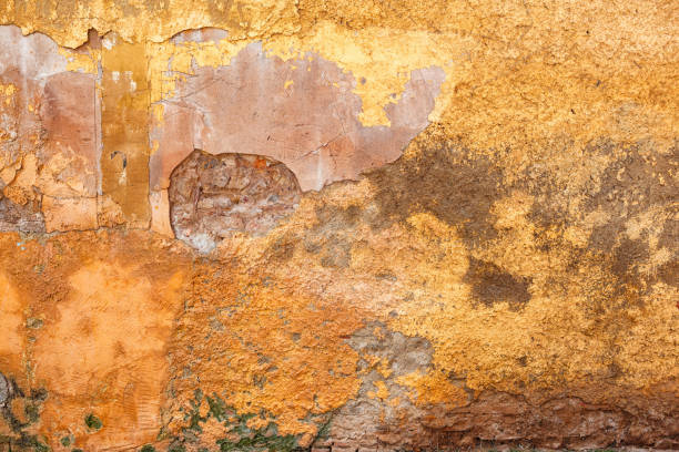 istock Textured Yellow Wall With Weathered Brick Base and Green Grass at the Bottom, Natural Daylight 2183728079