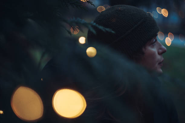 Woman glance behind a tree with christmas lights