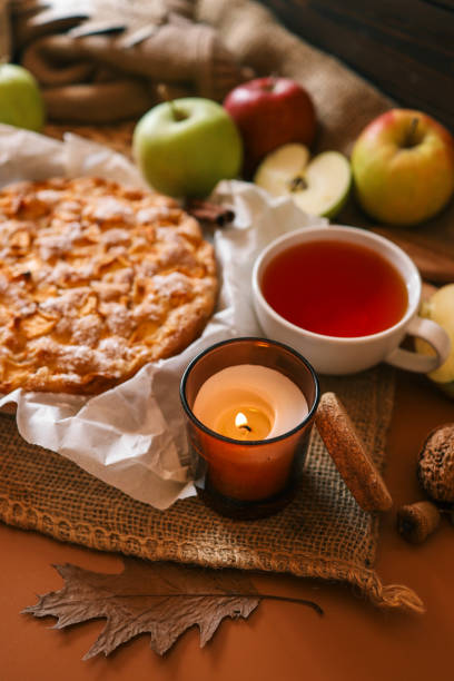 istock A cozy autumn setup featuring a freshly baked apple pie surrounded by apples, walnuts, a candle, and a warm drink 2183730896