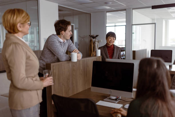 In a contemporary office setting, two business professionals hold a conversation. The man listens intently while the woman gestures, highlighting their collaborative spirit.